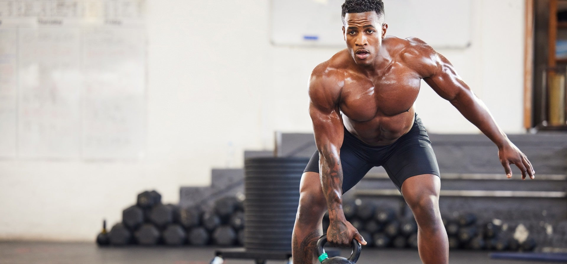 Muscular man lifting a kettlebell in a gym setting